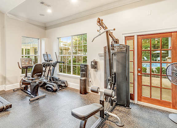 A home gym with a treadmill, elliptical machines, and a weight bench.