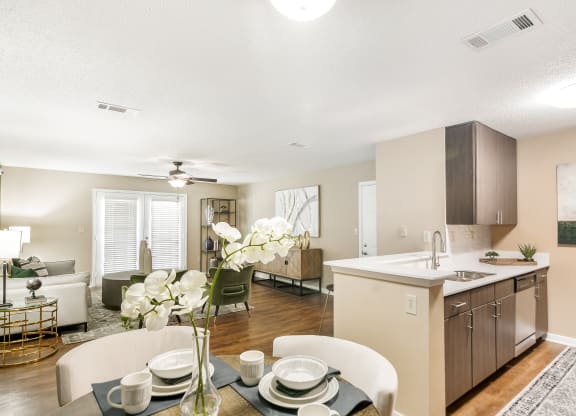 the living room and kitchen of an apartment with a dining table and chairs at Crossgates Apartment Homes, Starkville