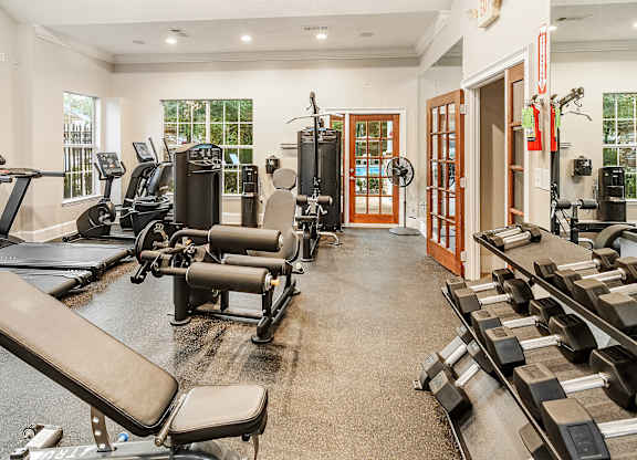 A gym with a variety of equipment including treadmills, weights, and exercise machines.