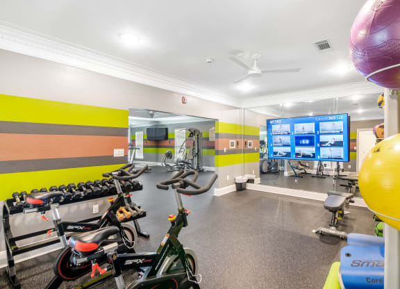 a workout room with bikes and weights and a tv at Avalon Apartment Homes in MS 39759
