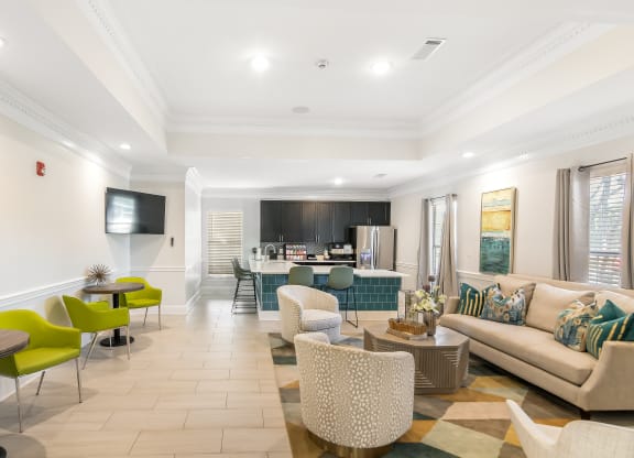 a living room with a couch and chairs and a kitchen at Avalon Apartment Homes in Starkville, Mississippi