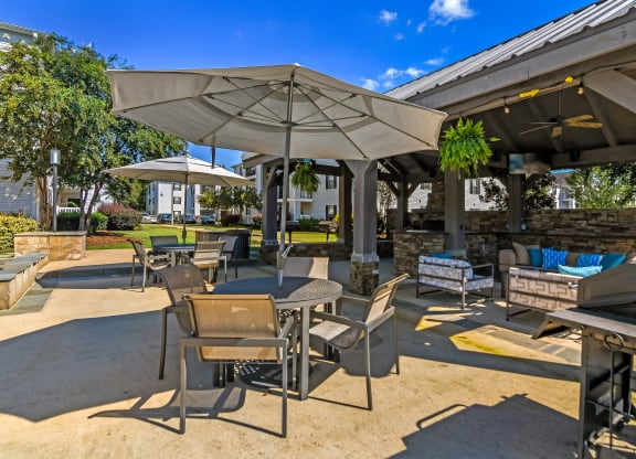 an outdoor patio with tables and chairs and umbrellas at Avalon Apartments Starkville, MS