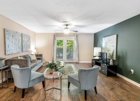 a living room with a couch and chairs and a ceiling fan at Avalon Apartment Homes in Starkville, 39759