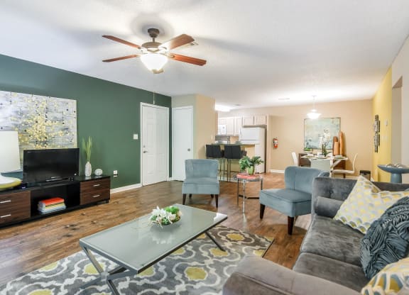 a living room with green walls and a ceiling fan at Avalon Apartments Starkville, MS