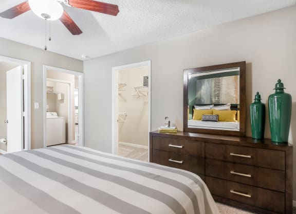 a bedroom with a bed and a dresser and a bathroom at Avalon Apartments Starkville, MS, 39759
