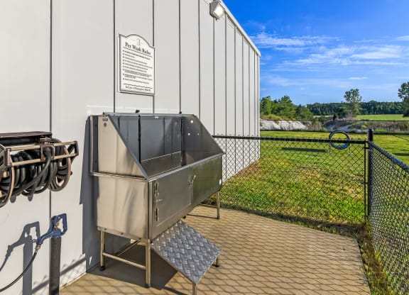 an outdoor patio with a grill and a building with a field of grass at Avalon Apartments Starkville, MS