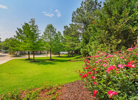 a park with green grass and trees and flowers at Lexington Pointe Apartment Homes in Oxford, MS 