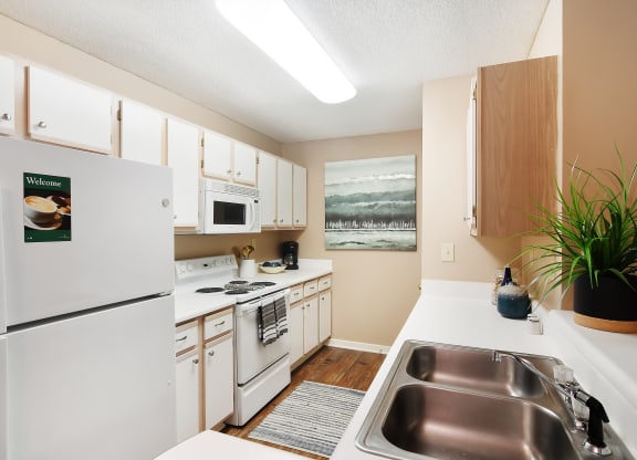 a kitchen with white appliances and a stainless steel sink at Lexington Pointe Apartment Homes in Oxford, MS 38655