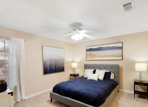 the master bedroom has a large bed and a ceiling fan at Lexington Pointe Apartment Homes in MS 38655