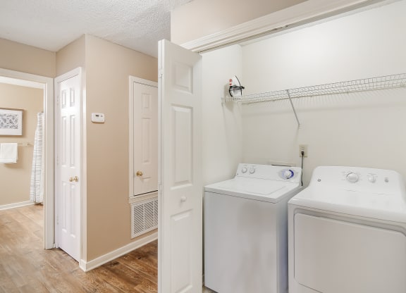 a laundry room with a washer and dryer and a door to a closet at Lexington Pointe Apartments in Oxford, MS 