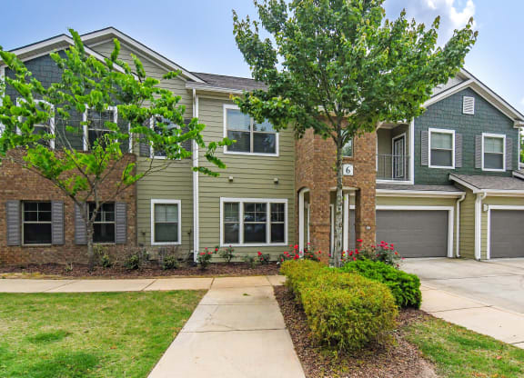 Property exterior with walking path and garage at Faulkner Flats Apartment Homes, Oxford, MS, Mississippi