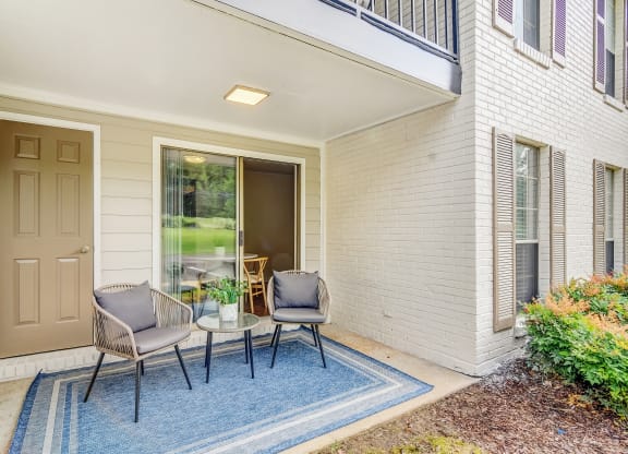 a patio with two chairs and a table on a blue rug at Cambridge Station Apartment Homes, Mississippi