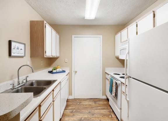 an empty kitchen with white appliances and counters and a white refrigerator at Parklane Apartment Homes, McComb