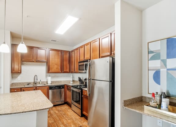 Kitchen with wooden closet and stainless steel appliances at Faulkner Flats Apartment Homes, Mississippi