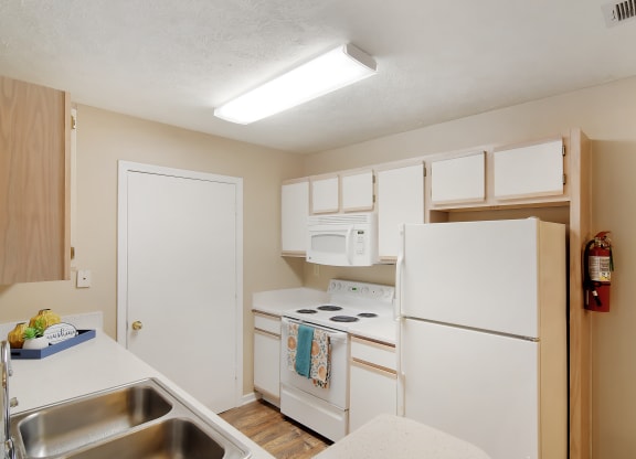 a kitchen with white appliances and a sink and a refrigerator  at Parklane Apartment Homes, McComb, Mississippi