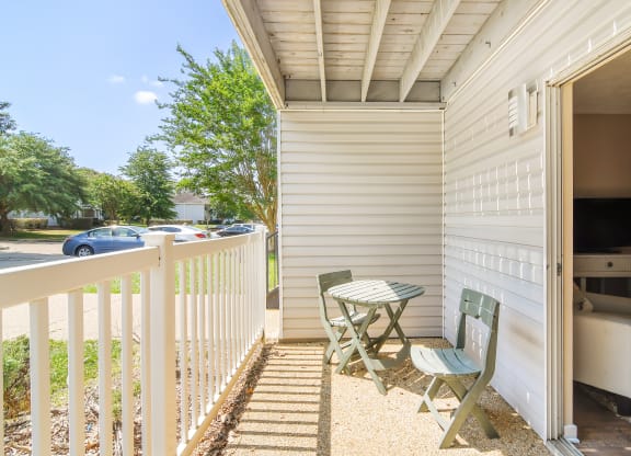 a balcony with a table and two chairs and a parking lot at Parklane Apartment Homes, McComb
