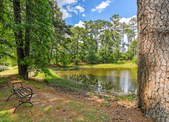 a bench sitting next to a pond at Parklane Apartment Homes, McComb