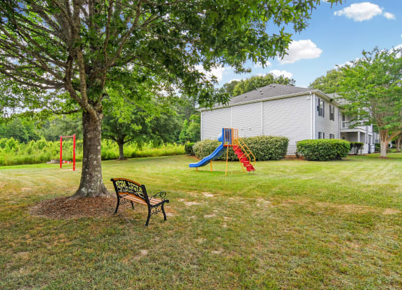 a park with a swing set and a bench in front of a house at Parklane Apartment Homes, McComb
