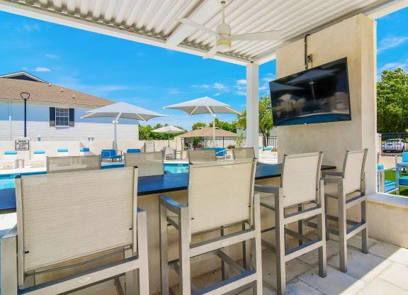 the backyard has a large patio with tables and chairs and a tv at The Vineyard of Olive Branch Apartment Homes, Olive Branch, Mississippi