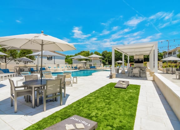 a swimming pool with tables and umbrellas at a resort at The Vineyard of Olive Branch Apartment Homes, Olive Branch