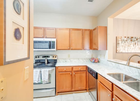 a kitchen with wooden cabinets and stainless steel appliances at The Vineyard of Olive Branch Apartment Homes, Mississippi 38654