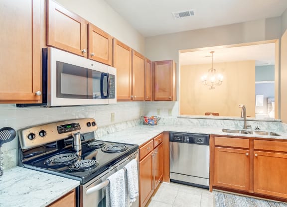 a kitchen with wood cabinets and a stove and a microwave at The Vineyard of Olive Branch Apartment Homes, Olive Branch, 38654