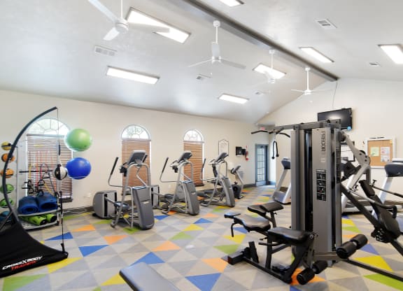a gym with cardio equipment and weights in a building with windows at Landing at Willow Bayou in Bossier City, LA 
