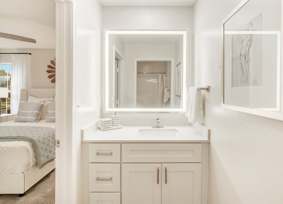a white bathroom with a sink and a mirror at The Oliver Apartment Homes in Olive Branch, MS 