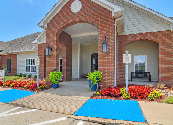 the entrance to a brick building with blue mats on the sidewalk at The Madison Apartment Homes in Tyler, Texas 75703