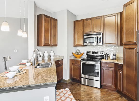 a kitchen with stainless steel appliances and granite counter tops at Wellington Grande Apartment Homes, Texas