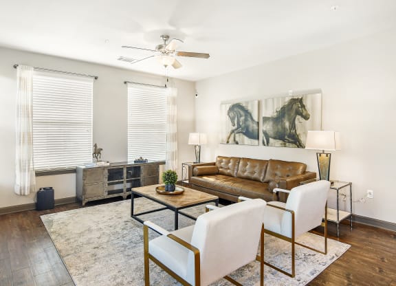 a living room with a leather couch and two white chairs at Wellington Grande Apartment Homes, Longview, TX, Texas