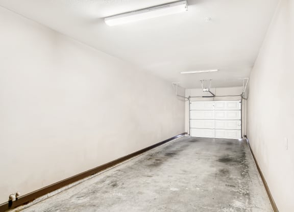 an empty garage with a white wall and a garage door at Wellington Grande Apartment Homes, Longview, TX, Texas