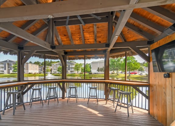 a covered deck with tables and chairs overlooking a body of water at Reserve at Gulf Hills Apartment Homes in Ocean Springs, Mississippi 39564