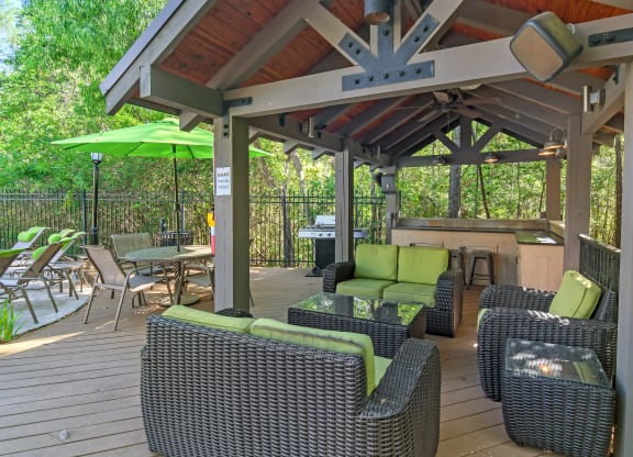 a covered patio with wicker furniture and a grill at Lagniappe of Biloxi Apartment Homes, Biloxi, MS, Mississippi
