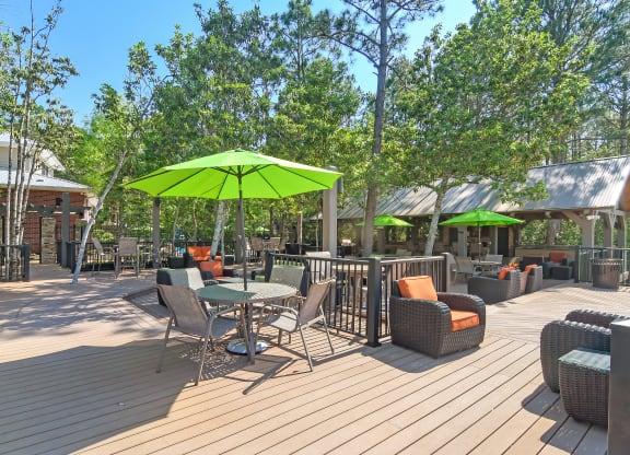 a patio with tables and chairs and a green umbrella at Lagniappe of Biloxi Apartment Homes, Biloxi, 39532