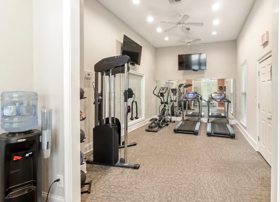 a home gym with cardio equipment and a television at Lagniappe of Biloxi Apartment Homes, Biloxi