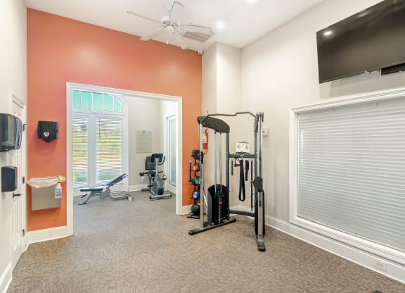 a home gym with exercise equipment and a tv at Lagniappe of Biloxi Apartment Homes, Biloxi, MS, 39532