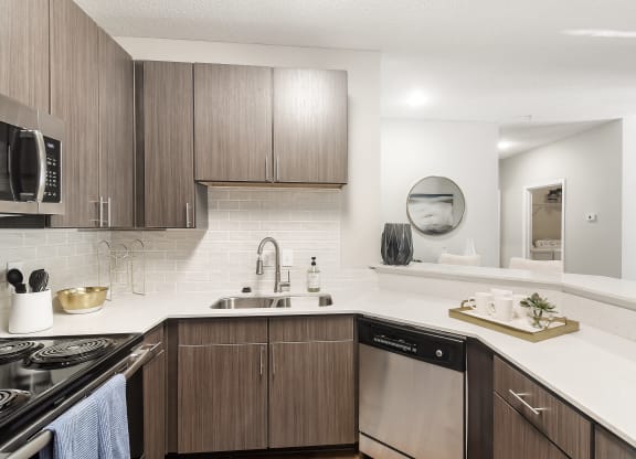 our spacious kitchen is equipped with stainless steel appliances and a white quartz counter top at Lagniappe of Biloxi Apartment Homes, Biloxi, MS