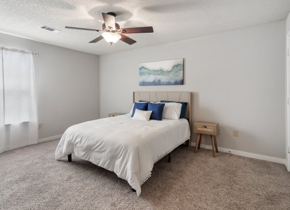 a bedroom with a bed and a ceiling fan at The Pointe Apartment Homes in Gautier, MS 39553