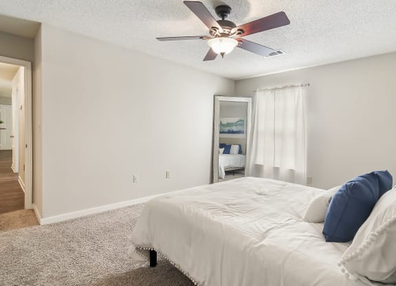 a bedroom with a large bed and a ceiling fan at The Pointe Apartment Homes in Gautier, 39553