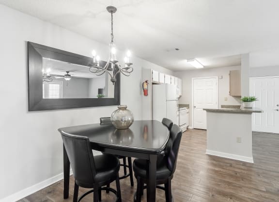 a dining room with a table and chairs and a kitchen at The Pointe Apartment Homes in Gautier, Mississippi 39553