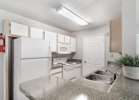a kitchen with white appliances and a granite counter top at The Pointe Apartment Homes in Gautier, 39553