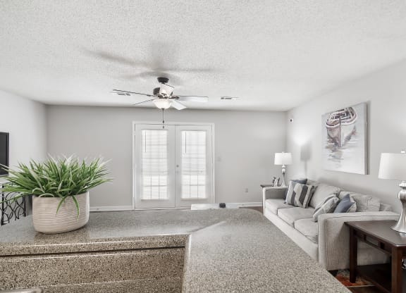 a living room with a couch and a ceiling fan at The Pointe Apartment Homes in Gautier, Mississippi 39553