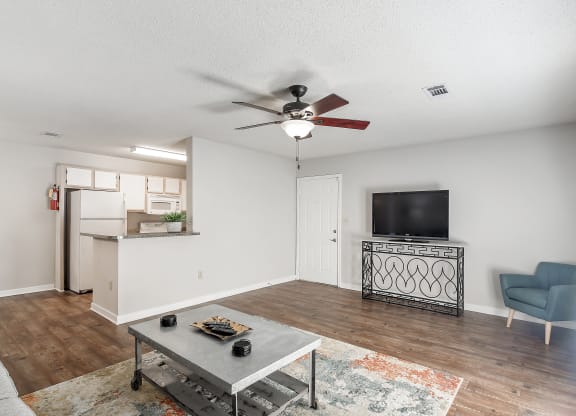 the living room and kitchen of a studio apartment with a tv at The Pointe Apartment Homes in Gautier, Mississippi 