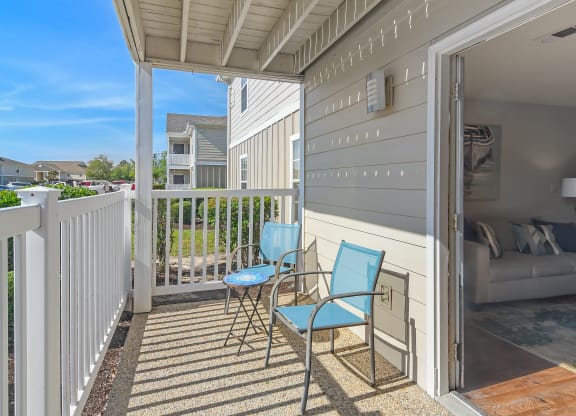 a patio with two chairs and a couch on a balcony at The Pointe Apartment Homes in MS 39553