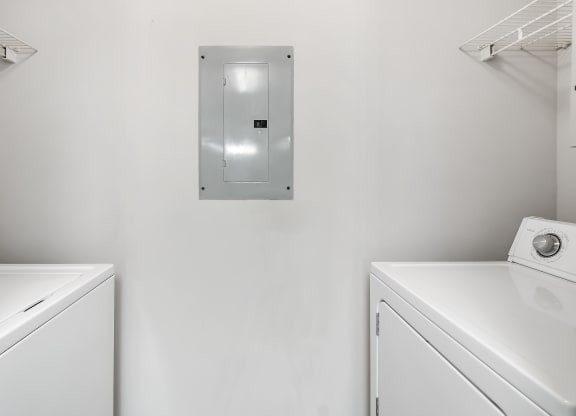 a washer and dryer in a white laundry room at The Pointe Apartment Homes in Gautier, MS 