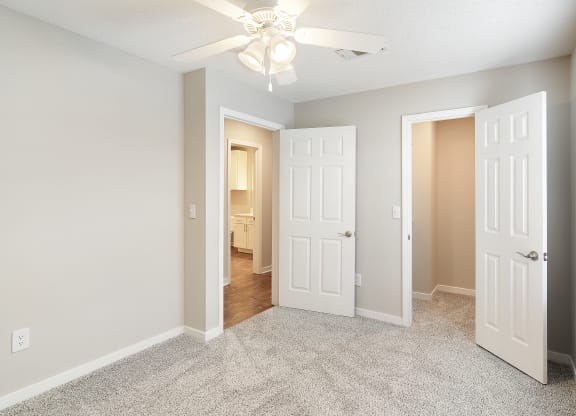 an empty bedroom with white doors and a ceiling fan at The Woodlands Apartment Homes, Meridian, Mississippi