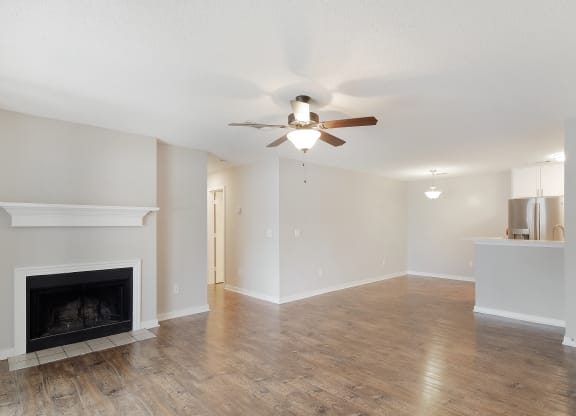 an empty living room with a ceiling fan and a fireplace at The Woodlands Apartment Homes, Meridian, MS, 39301