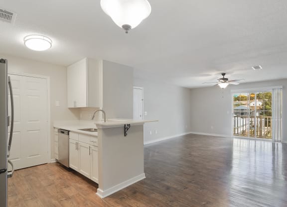 an empty kitchen and living room with a door to a balcony at The Woodlands Apartment Homes, Meridian, 39301