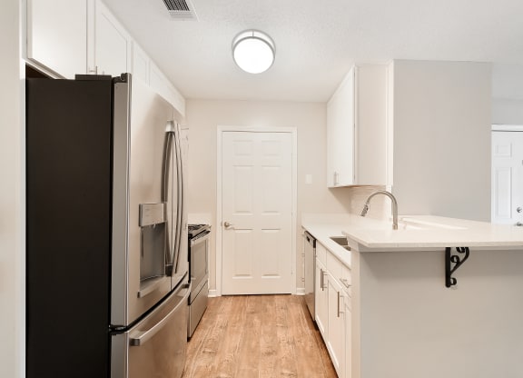 an empty kitchen with stainless steel appliances and a white counter top at The Woodlands Apartment Homes, Meridian, MS
